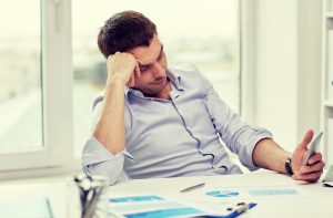 Man looking at cell phone office unproductive